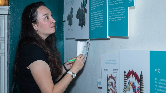 A woman looks at an exhibit panel on the wall.